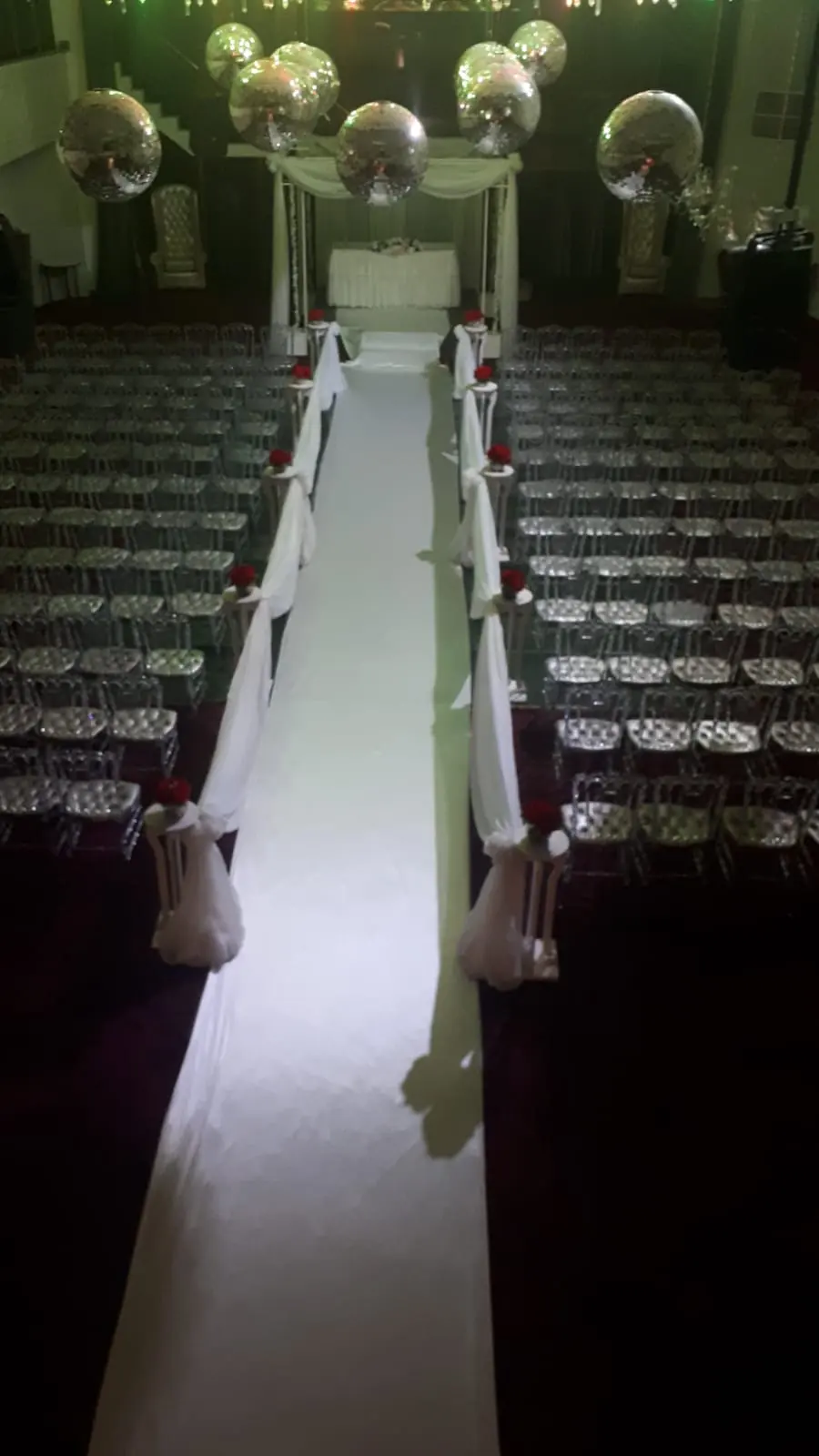 Pasillo blanco iluminado para una ceremonia en el Salón Real de Victoria Palace